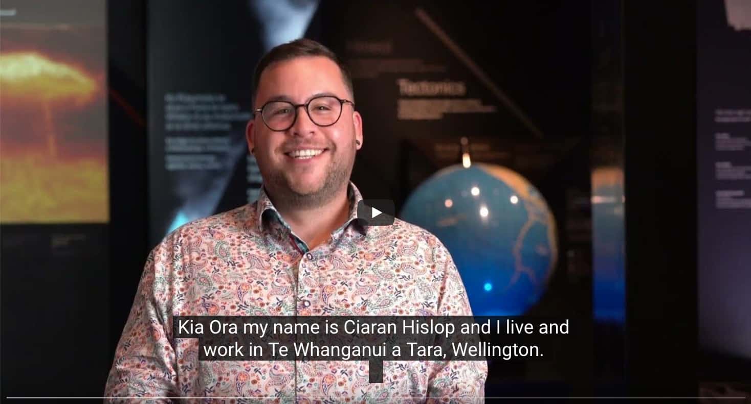 A man is smiling in front of a video screen.