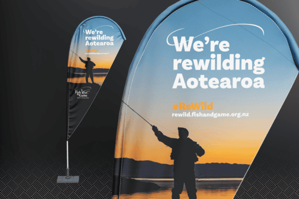 Banner promoting Fish & Game's rewilding campaign with the text "We're rewilding Aotearoa" and a website link. Image shows a person fishing at sunset.